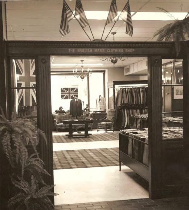 Archival photograph of The English Man's Clothing Shop entrance with Union Jack and American flags